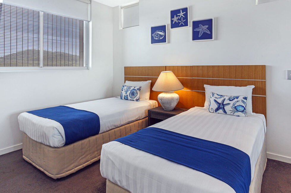 Pool View 2 Bedroom Apartment twin bedroom with blue throws