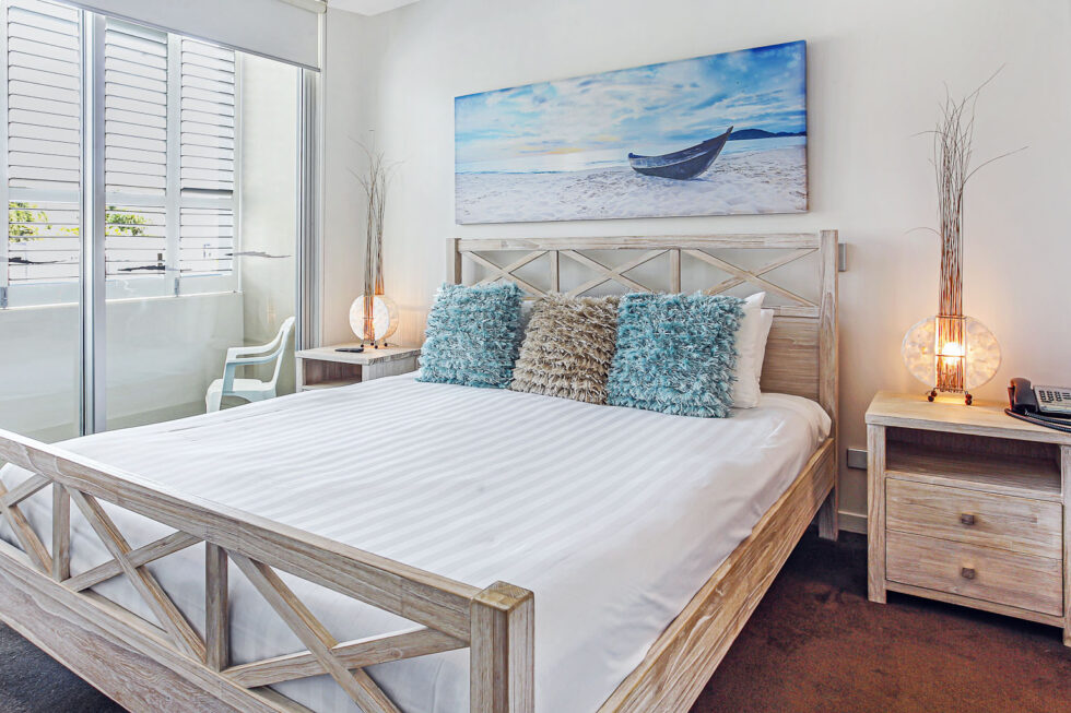 Pool View 2 Bedroom Apartment master bedroom with coastal wall art