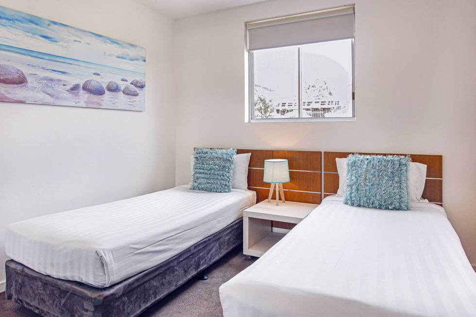 Pool View 2 Bedroom Apartment twin bedroom with shell artwork