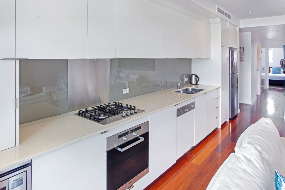 Pool View 2 Bedroom Apartment white kitchen with timber floors