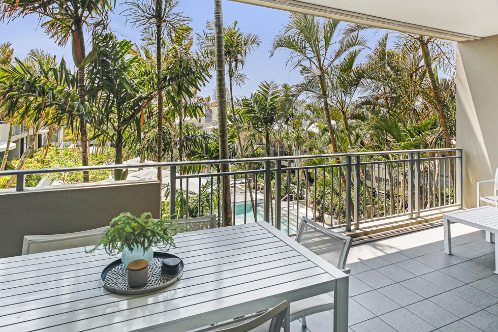 Pool View 2 Bedroom Apartment balcony dining table overlooking palms