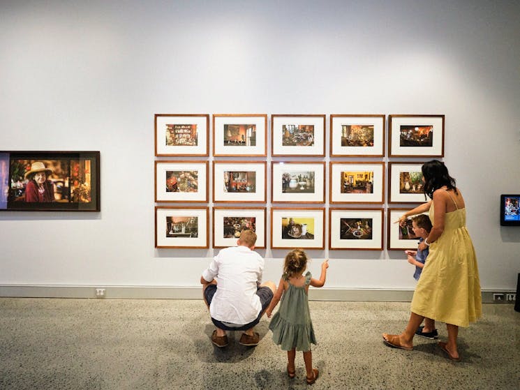 A family explores framed artwork together at the Tweed Regional Gallery, a cultural highlight of Northern NSW getaways for families.