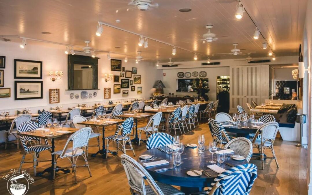 cabarita beach restaurants interior at Paper Daisy, elegant coastal dining room with blue chevron chairs, set tables, and warm ambient lighting